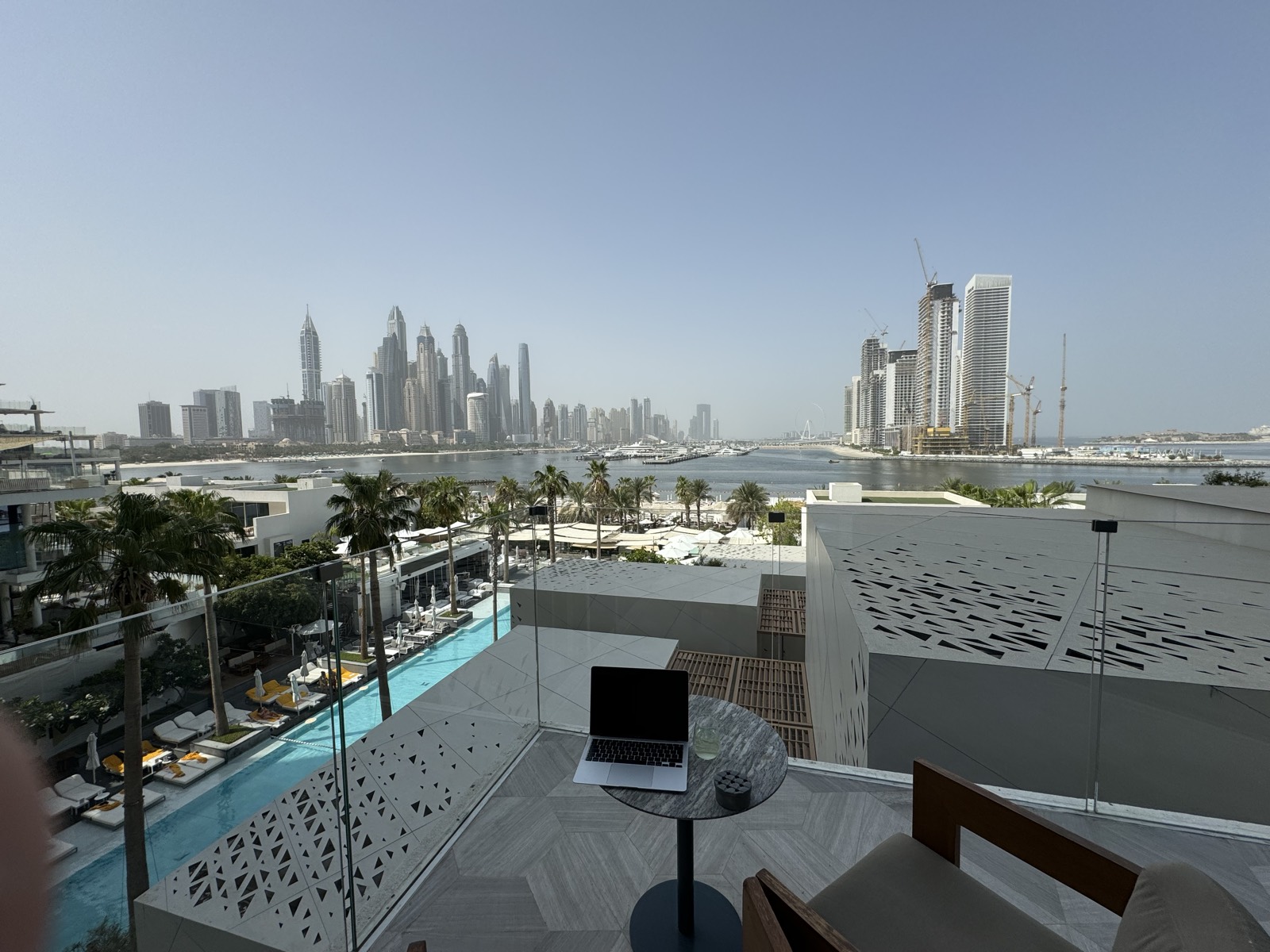 Laptop on a terrace table overlooking Palm Jumeirah and the Dubai Marina skyline